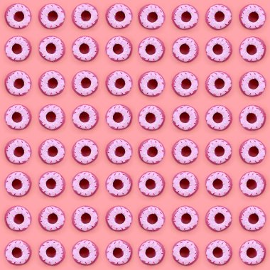 Birçok küçük plastik donuts bir pastel renkli arka plan üzerinde yatıyor. Düz yatıyordu en az desen. Üstten görünüm