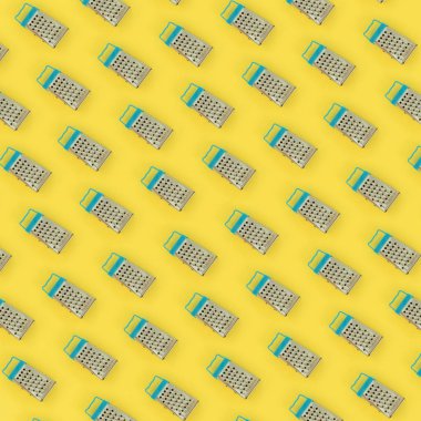 Küçük paslanmaz çelik rende renkli kağıt üzerine pastel yatıyor. Mutfak aksesuarları. Yemek pişirmek için araçlar. Düz yatıyordu üstten görünüm