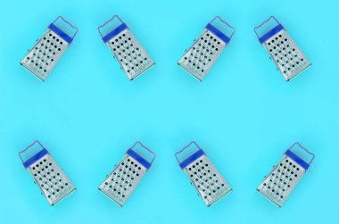 Küçük paslanmaz çelik rende renkli kağıt üzerine pastel yatıyor. Mutfak aksesuarları. Yemek pişirmek için araçlar. Düz yatıyordu üstten görünüm