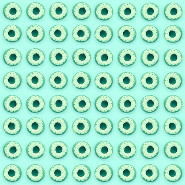 Muchos pequeños donuts de plástico se encuentra en un fondo de colores pastel. Piso establecer un patrón mínimo. Vista superior — Foto de Stock