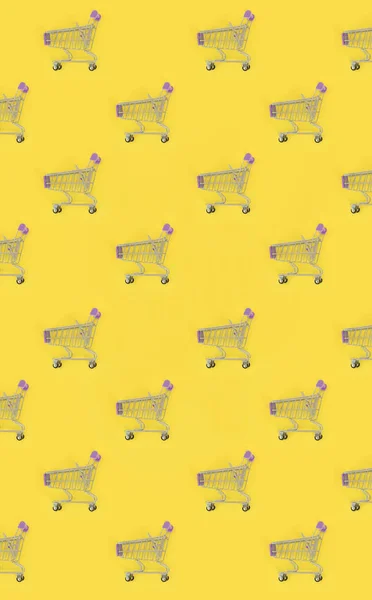 Shopping addiction, shopping lover or shopaholic concept. Many small empty shopping carts perform a pattern on a pastel colored paper background. Flat lay composition, top view — Stock Photo, Image