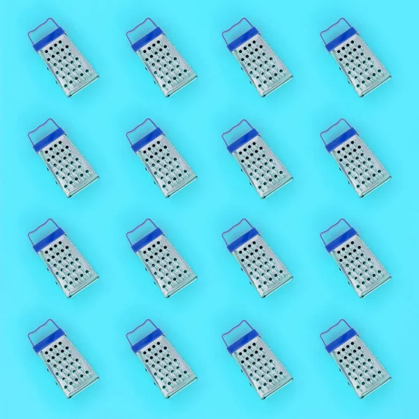 Small stainless steel graters lies on a pastel colored paper. Kitchen accessories. Tools for cooking. Flat lay top view — Stock Photo, Image