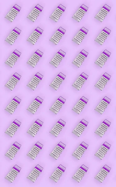 Small stainless steel graters lies on a pastel colored paper. Kitchen accessories. Tools for cooking. Flat lay top view — Stock Photo, Image