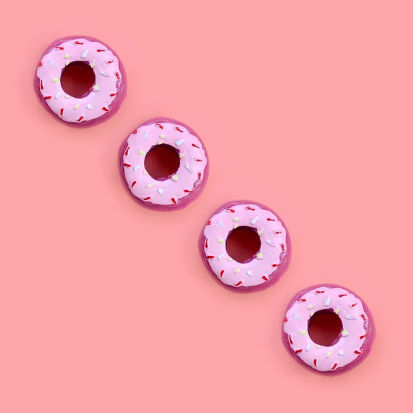 Muchos pequeños donuts de plástico se encuentra en un fondo de colores pastel. Piso establecer un patrón mínimo. Vista superior —  Fotos de Stock