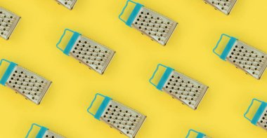 Küçük paslanmaz çelik rende renkli kağıt üzerine pastel yatıyor. Mutfak aksesuarları. Yemek pişirmek için araçlar. Düz yatıyordu üstten görünüm