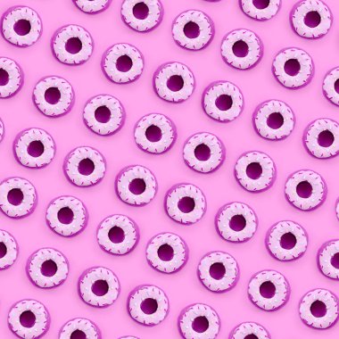 Birçok küçük plastik donuts bir pastel renkli arka plan üzerinde yatıyor. Düz yatıyordu en az desen. Üstten görünüm