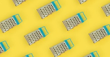 Küçük paslanmaz çelik rende renkli kağıt üzerine pastel yatıyor. Mutfak aksesuarları. Yemek pişirmek için araçlar. Düz yatıyordu üstten görünüm