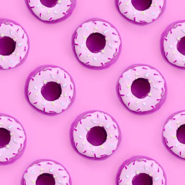 Birçok küçük plastik donuts bir pastel renkli arka plan üzerinde yatıyor. Düz yatıyordu en az desen. Üstten görünüm