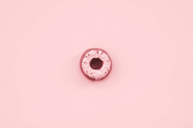 Tek küçük plastik çörek bir pastel renkli arka plan üzerinde yatıyor. Düz yatıyordu en az kompozisyon. Üstten görünüm