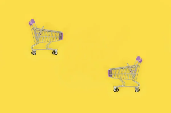Nákupní závislost, milence nebo shopaholic koncept nákupu. Malý prázdný nákupní vozík leží na pastelové barevné papírové pozadí. Plochá laických minimální složení, pohled shora — Stock fotografie
