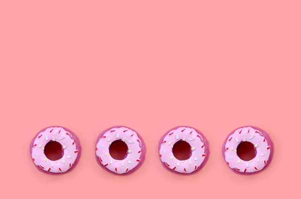 Muchos pequeños donuts de plástico se encuentra en un fondo de colores pastel. Piso establecer un patrón mínimo. Vista superior — Foto de Stock