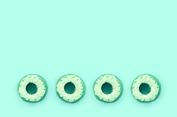 Many small plastic donuts lies on a pastel colorful background. Flat lay minimal pattern. Top view — Stock Photo, Image