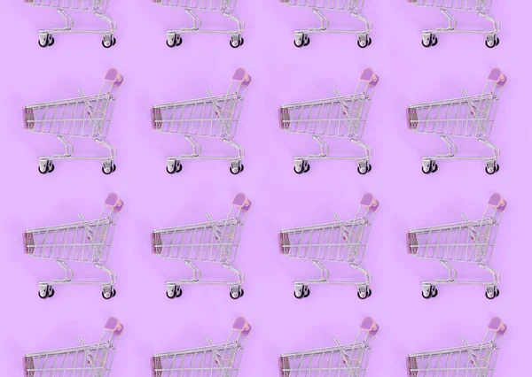 Shopping addiction, shopping lover or shopaholic concept. Many small empty shopping carts perform a pattern on a pastel colored paper background. Flat lay composition, top view — Stock Photo, Image