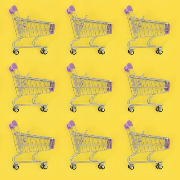 Addiction au shopping, amant du shopping ou concept shopaholic. Beaucoup de petits chariots vides effectuent un motif sur un fond de papier de couleur pastel. Composition de la couche plate, vue de dessus — Photo