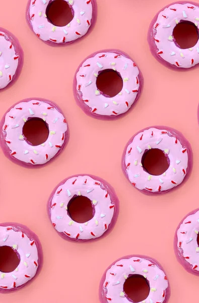 Birçok küçük plastik donuts bir pastel renkli arka plan üzerinde yatıyor. Düz yatıyordu en az desen. Üstten görünüm — Stok fotoğraf