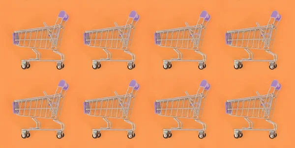 Shopping addiction, shopping lover or shopaholic concept. Many small empty shopping carts perform a pattern on a pastel colored paper background. Flat lay composition, top view — Stock Photo, Image