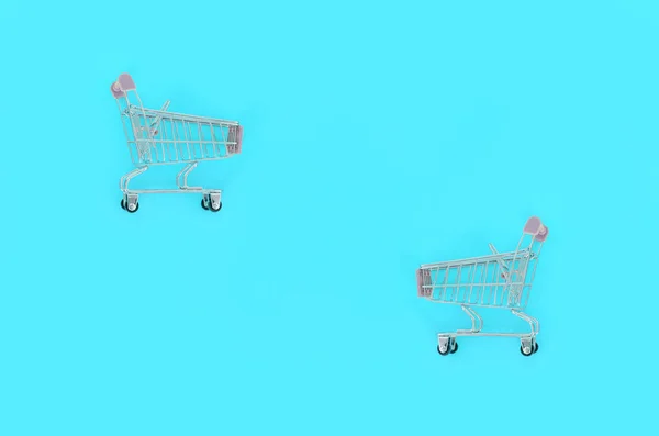 Adicción a las compras, amante de las compras o concepto adicto a las compras. Pequeño carrito de compras vacío se encuentra sobre un fondo de papel de color pastel. Redacción plana composición mínima, vista superior —  Fotos de Stock