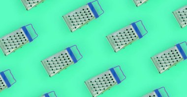 Küçük paslanmaz çelik rende renkli kağıt üzerine pastel yatıyor. Mutfak aksesuarları. Yemek pişirmek için araçlar. Düz yatıyordu üstten görünüm