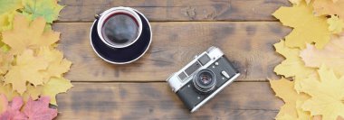 Bir fincan çay ve bir arka plan yüzeyi koyu kahverengi renk doğal ahşap kurulların düşen sonbahar yaprakları sararma kümesi arasında eski bir fotoğraf makinesi