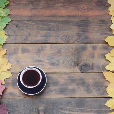 Arka plan koyu kahverengi renk doğal ahşap kurullarında yüzeyinde düşmüş sonbahar sararma kümesi arasında çay yaprakları