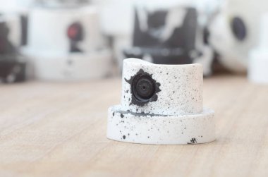 Gri bir karşı ahşap bir yüzey üzerinde yalan birkaç plastik bir boya püskürtme başlıklarından arka plan duvar. Kapaklar siyah boya bulaşmış. Sokak sanatı ve grafiti kavramı