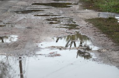 Fotoğraf ile yağmurlu havalarda büyük su birikintileri yok edilen bir yol parçasının
