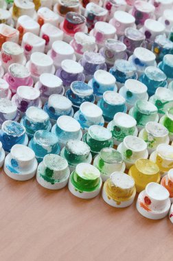 Bir çok farklı renklere bulaşmış grafiti çizim için bir boya püskürtme başlıklarından bir desen. Plastik kapaklar gökkuşağı rengi oluşturan birçok satır düzenlenir