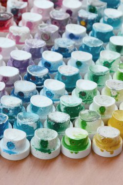 Bir çok farklı renklere bulaşmış grafiti çizim için bir boya püskürtme başlıklarından bir desen. Plastik kapaklar gökkuşağı rengi oluşturan birçok satır düzenlenir
