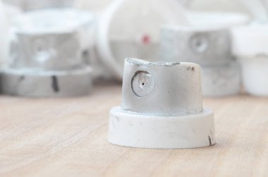 Gri bir karşı ahşap bir yüzey üzerinde yalan birkaç plastik bir boya püskürtme başlıklarından arka plan duvar. Kapaklar krom boya bulaşmış. Sokak sanatı ve grafiti kavramı