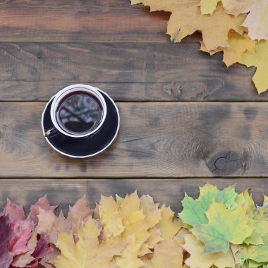 Arka plan koyu kahverengi renk doğal ahşap kurullarında yüzeyinde düşmüş sonbahar sararma kümesi arasında çay yaprakları