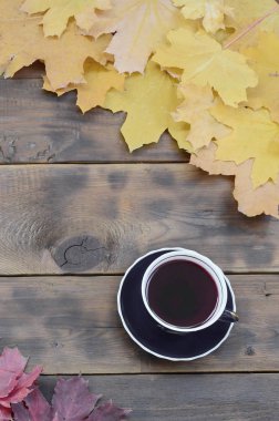 Arka plan koyu kahverengi renk doğal ahşap kurullarında yüzeyinde düşmüş sonbahar sararma kümesi arasında çay yaprakları