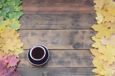 Arka plan koyu kahverengi renk doğal ahşap kurullarında yüzeyinde düşmüş sonbahar sararma kümesi arasında çay yaprakları