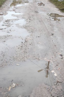 Fotoğraf ile yağmurlu havalarda büyük su birikintileri yok edilen bir yol parçasının