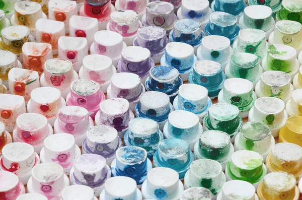 A pattern from a many nozzles from a paint sprayer for drawing graffiti, smeared into different colors. The plastic caps are arranged in many rows forming the color of the rainbow