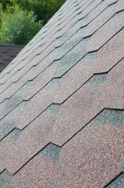 The texture of the roof with bituminous coating. Rough bituminous mosaic of red and brown flowers. Waterproof roofing