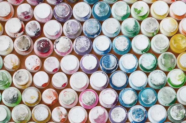 A pattern from a many nozzles from a paint sprayer for drawing graffiti, smeared into different colors. The plastic caps are arranged in many rows forming the color of the rainbow