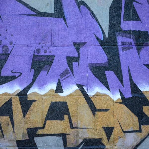 Fragment of graffiti drawings. The old wall decorated with paint stains in the style of street art culture. Colored background texture in purple tones.