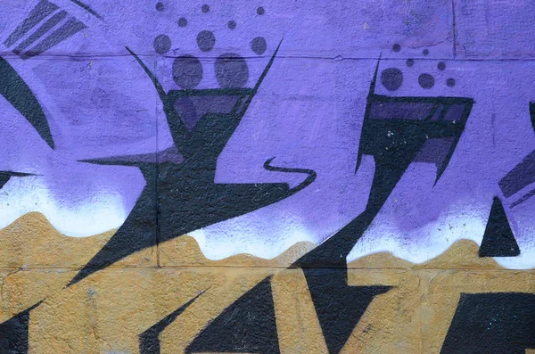 Fragment of graffiti drawings. The old wall decorated with paint stains in the style of street art culture. Colored background texture in purple tones.