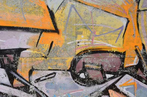Fragment of graffiti drawings. The old wall decorated with paint stains in the style of street art culture. Colored background texture in warm tones.