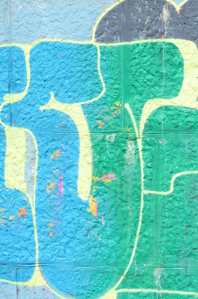 Fragment of graffiti drawings. The old wall decorated with paint stains in the style of street art culture. Colored background texture in green tones.