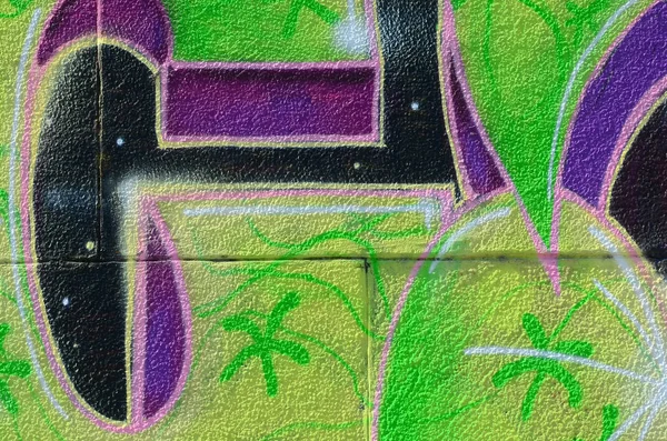 Fragment of graffiti drawings. The old wall decorated with paint stains in the style of street art culture. Colored background texture in green tones.