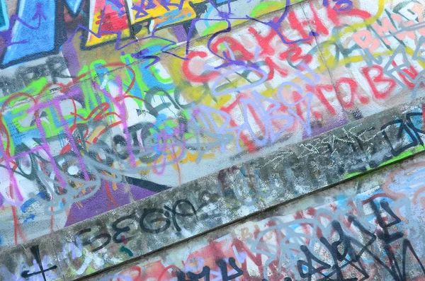 Fragment of graffiti tags. The old wall is spoiled with paint stains in the style of street art culture.