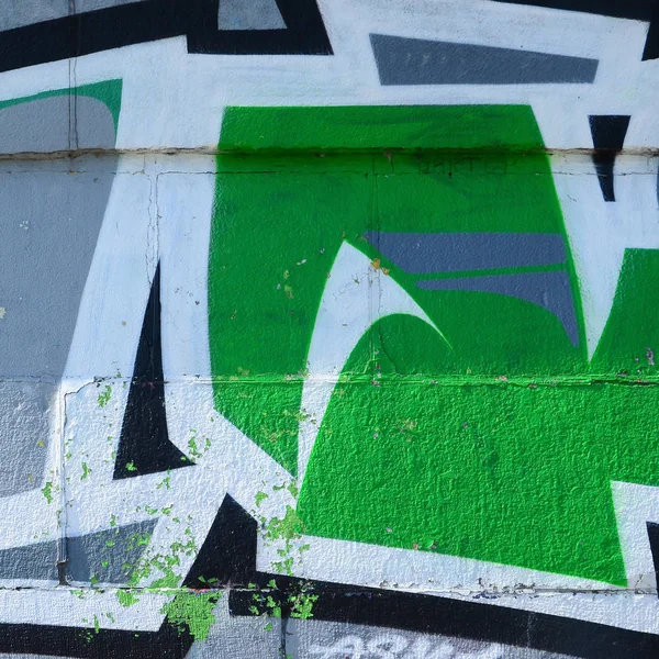 Fragment of graffiti drawings. The old wall decorated with paint stains in the style of street art culture. Colored background texture in green tones.