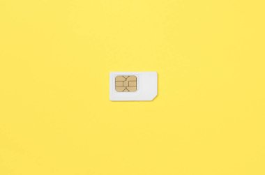 Abone kimlik modülü. Parlak sarı renkli arka plan üzerinde beyaz yeni SIM kart. Üstten görünüm en az düz yatıyordu