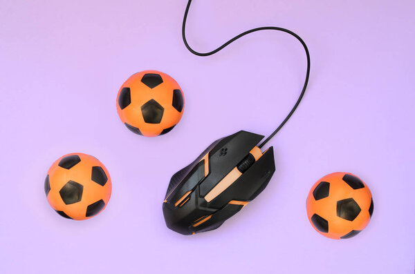 Оптическая игровая мышь и маленькие оранжевые футбольные мячи
