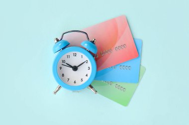 Küçük mavi çalar saat renkli kredi kartlarında yatıyor. Kavramını modern hızlı online bankacılık ve hızlı finansal faaliyetler