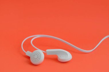 Beyaz modern kulaklık bir parlak kırmızı zemin üzerine yalan. Müzik dinleme hayranları için bir şablon