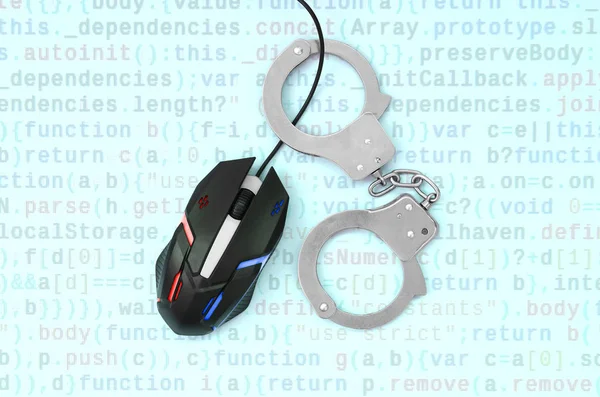 Computer mouse in a police color is chained in handcuffs on the background of the program code. The concept of combating computer crime, hackers and piracy. Flat lay top view