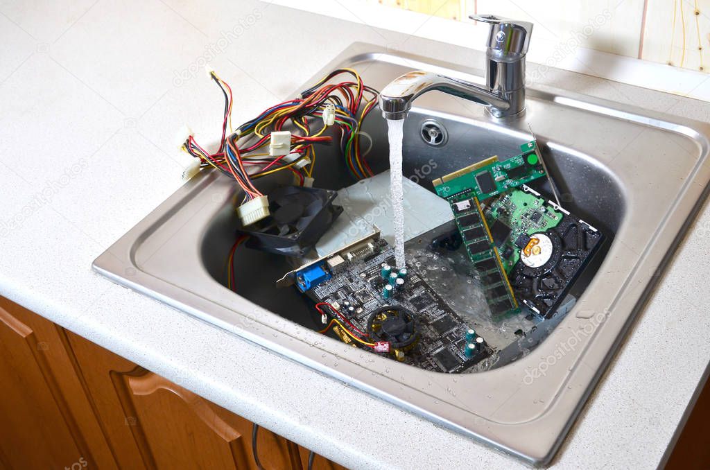 Cleaning the hardware concept. Washing the motherboard, hard drive and computer power supply in kitchen sink. Also a symbol for making a big mistake