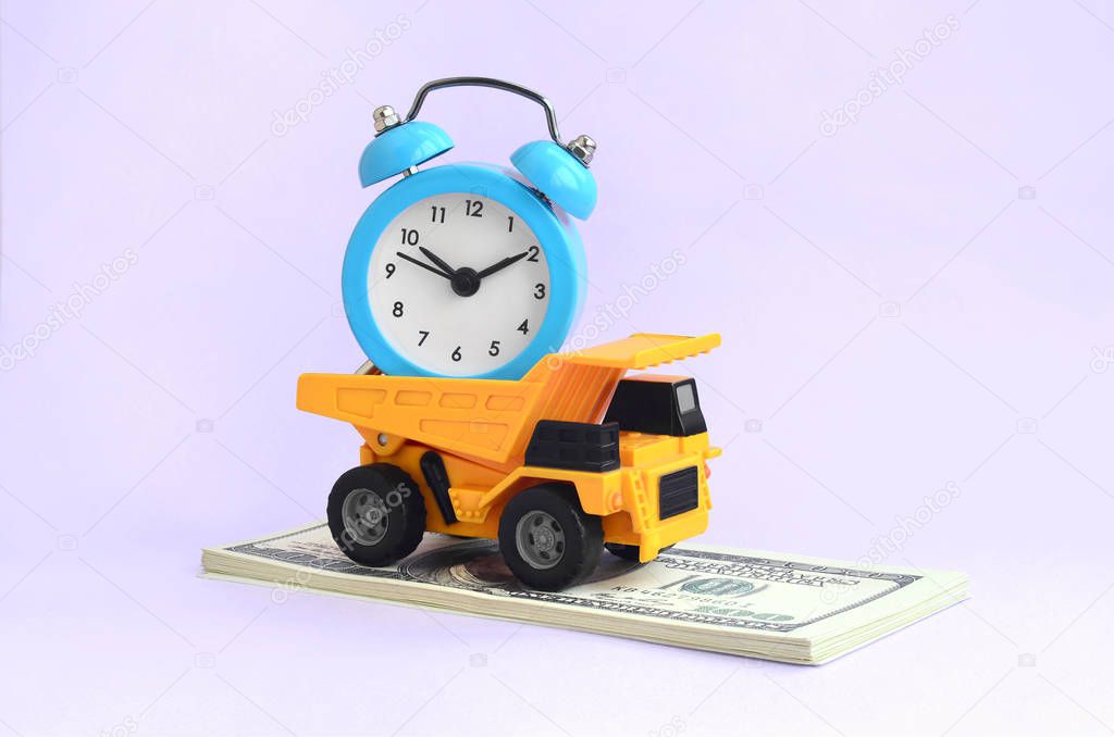 A dump truck loaded with an alarm clock is on a wad of dollar bills. The concept of optimization and rational time management. Saving of time and delegation of work